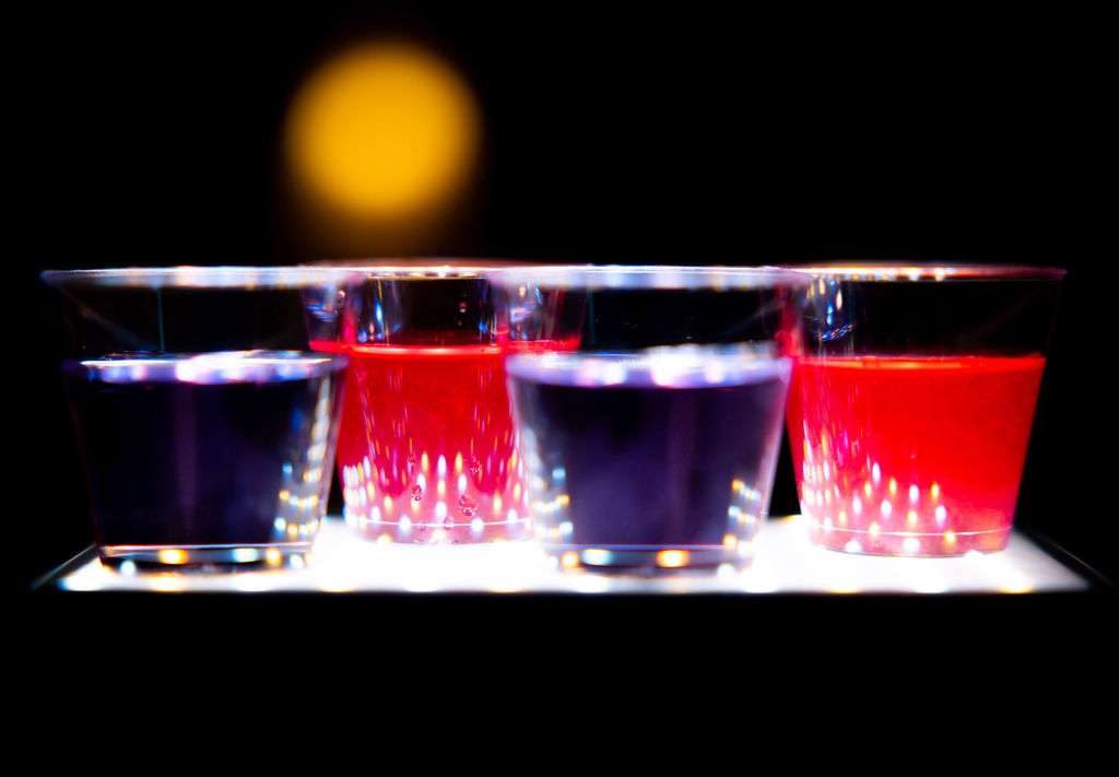 Close up photograph of brightly coloured cocktails in clear tumbler glasses.