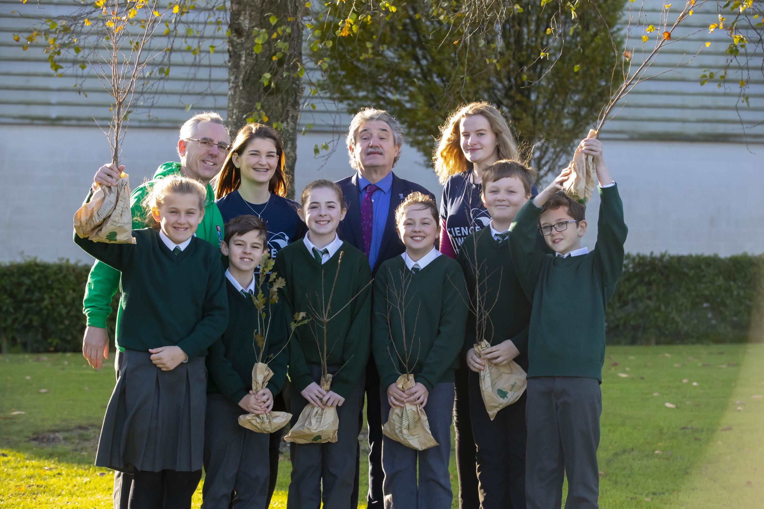 School children, teachers and Minister holding trees to plant for Science Week 2019.